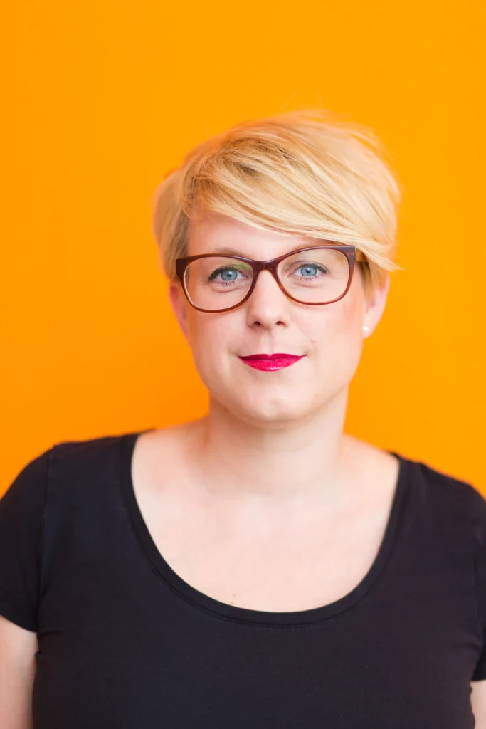 Frau-blond-roter-lippenstift-brille-tshirt-schwarz-hintergrund-orange