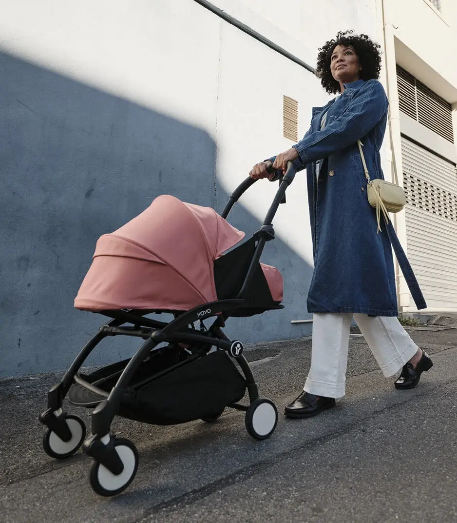 frau-spazieren-kinderwagen-rosa-blaue-jacke-weisse-hose