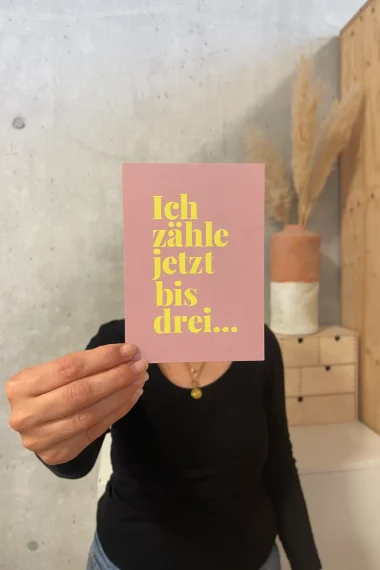 postkarte-frau-vor-gesicht-rosa-gelbe-schrift-ich-zähle-jetzt-bis-drei